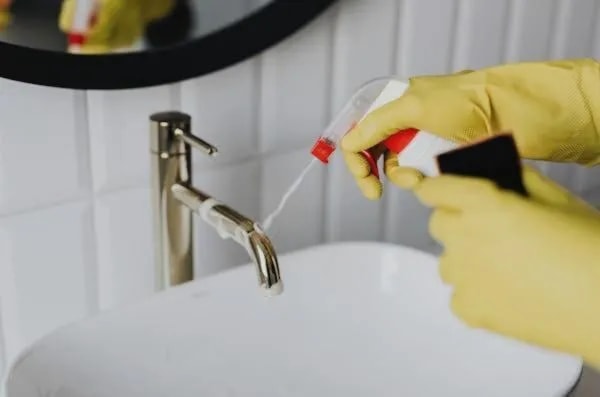 spraying cleaning solution bathroom sink with mirror